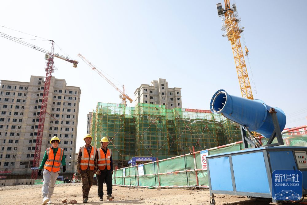 ↑4月3日，施工人员从中铁二十局承建的兰州新区中川园区城中村改造项目建设现场走过。