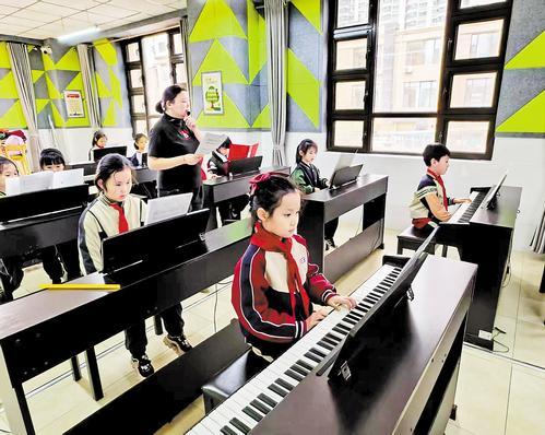 3月13日,邯郸市丛台区荀子实验小学学生在课后服务机构教师指导下练习弹琴。本报记者 刘剑英摄