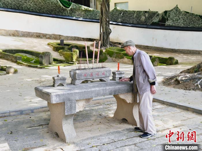 80岁的守墓人陈丰在清理落叶。叶艺琳摄