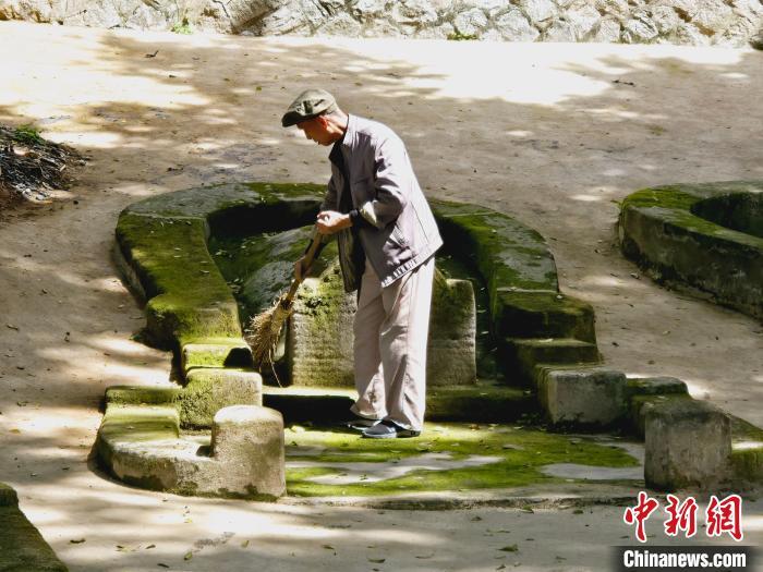 80岁的守墓人陈丰在清扫落叶。叶艺琳摄