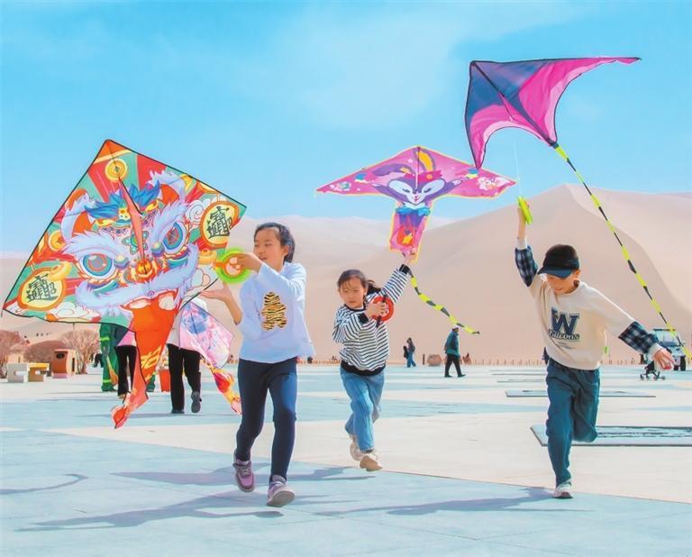 孩子们参加在敦煌市鸣沙山下举办的风筝比赛 新甘肃·甘肃日报通讯员 王斌银