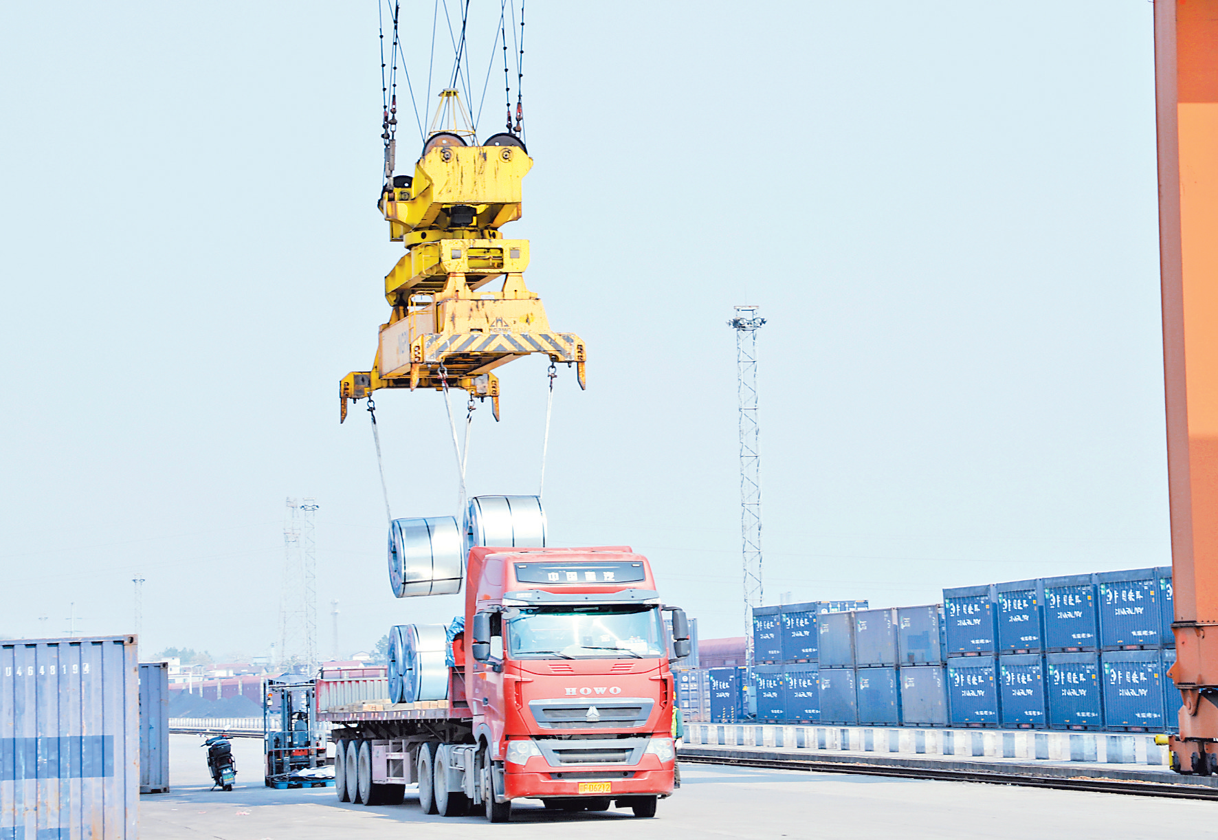 在铁路港集装箱装卸作业区，工作人员操作龙门吊进行装货。