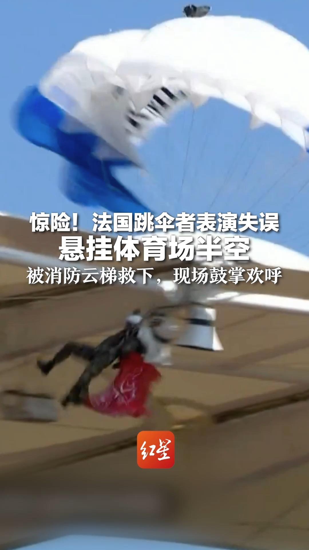 惊险！法国跳伞者表演失误悬挂体育场半空 被消防云梯救下，现场鼓掌欢呼