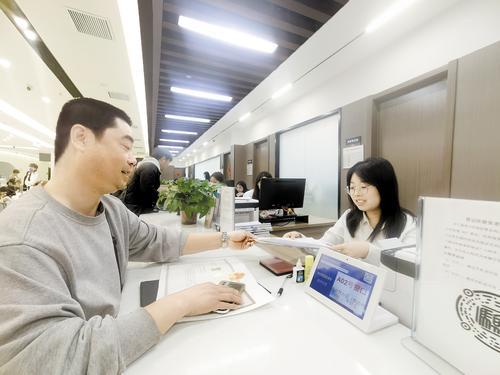 4月2日，秦皇岛高永商贸有限公司工作人员李海涛（左）在海港区政务服务大厅办理企业迁址手续。本报记者 孙也达摄