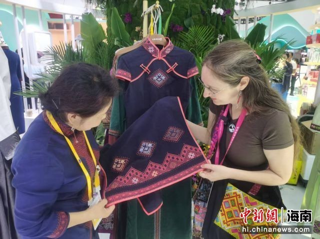 15日，美国设计师谢敏(右)走进展台参观有着黎锦元素的服饰。张茜翼 摄