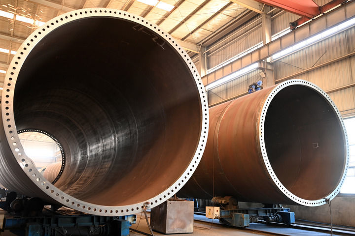 2025年3月11日，在位于张掖市高台县的甘肃创腾电力装备有限责任公司生产车间，工人在风机塔筒生产线上作业。新华社记者　范培珅　摄