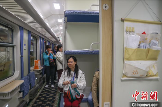 4月13日,江西南昌站,搭乘赣闽首趟银发旅游专列的旅客坐在车厢里等待发车,车厢墙壁上挂置了老花镜、针线包等适老服务用品。刘力鑫 摄