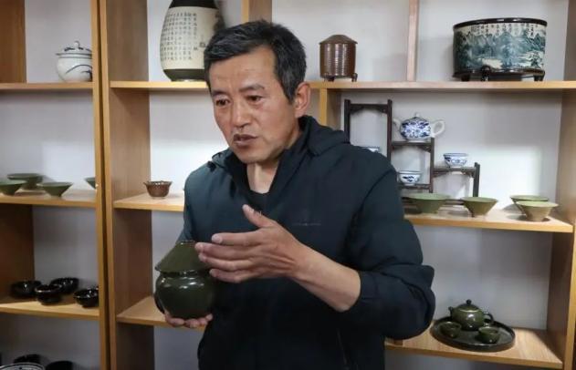 （非遗传承人正在介绍瓷器）