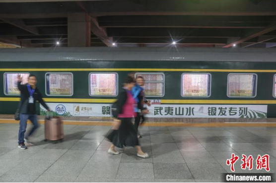 图为4月13日,江西南昌站,乘坐赣闽首趟银发旅游专列的旅客从列车旁走过。刘力鑫 摄