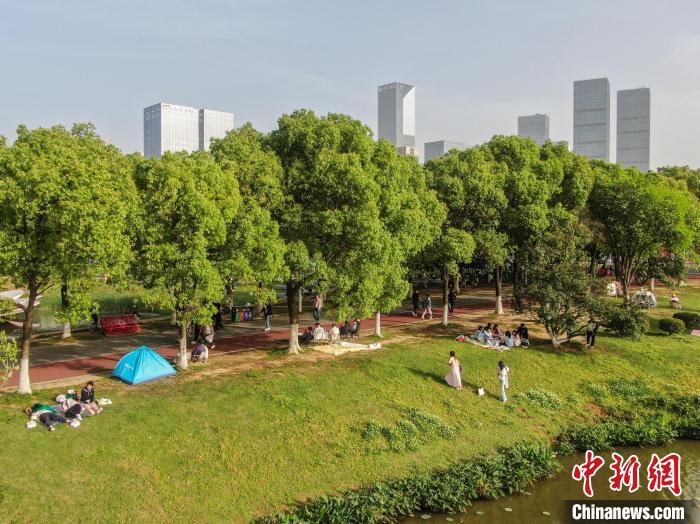 4月13日，江西南昌高新区艾溪湖湿地公园，市民在公园草坪上露营。当日南昌天气晴好，艾溪湖湿地公园绿意盎然，不少市民来到公园游玩，乐享周末悠闲时光。(无人机照片)中新社记者 刘力鑫 摄