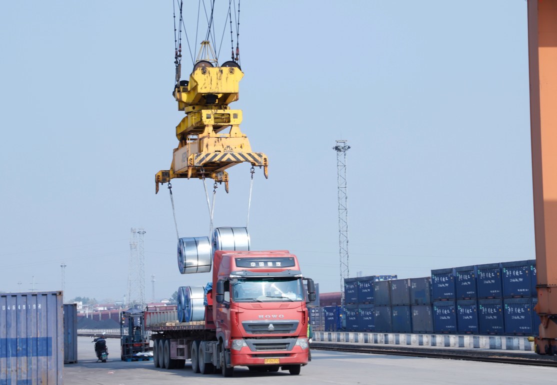 在铁路港集装箱装卸作业区,工作人员操作龙门吊进行装货。