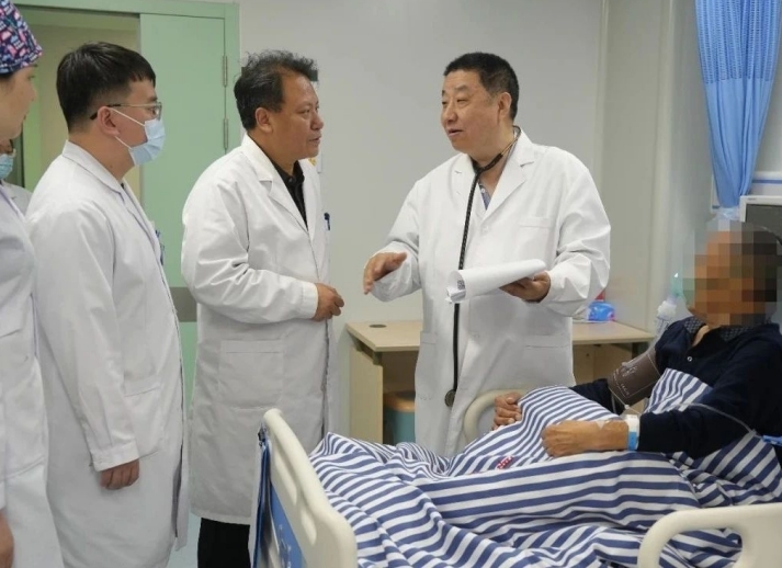 图为汝磊生教授（右一）开展带教查房