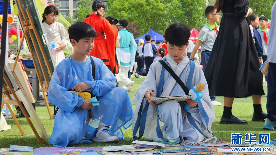 4月18日，在南阳市第二完全学校举办的图书淘宝市场活动中，孩子们正在挑选心仪的书籍。