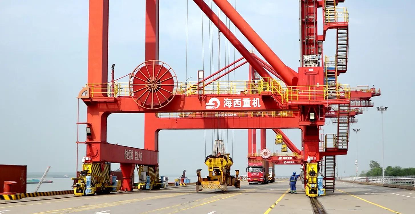 图为：位于江西九江市彭泽县的九江红光国际港，工作人员正在装卸集装箱，一派繁忙景象。（彭泽县融媒体中心 供图）