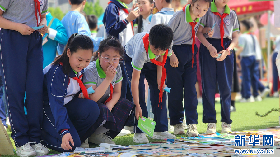 4月18日，在南阳市第二完全学校举办的图书淘宝市场活动中，孩子们正在挑选心仪的书籍。