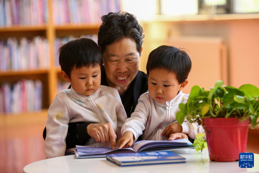 4月22日，在山东省济南市图书馆中山公园馆，长辈陪伴一对双胞胎小朋友阅读。新华社发（郝鑫城摄）