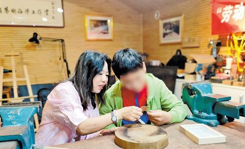 5月1日，“爱心妈妈”陈静（左）与浩浩一起制作铁板浮雕作品。 本报记者 孙青摄
