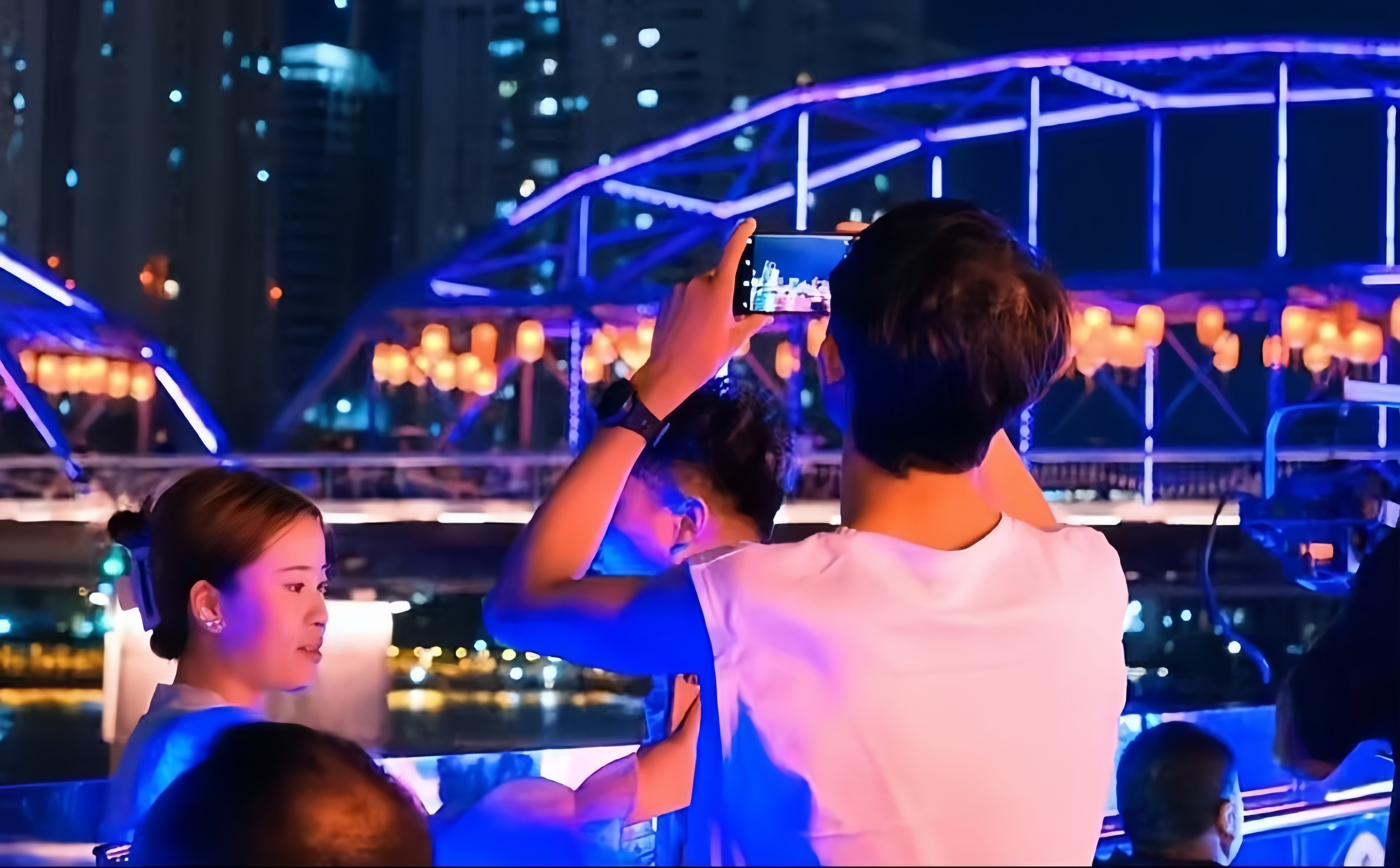 游客在游船上拍摄中山桥岸边夜景