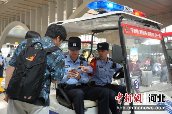  图为石家庄站派出所民警在候车室为旅客指路。 左文宇 摄