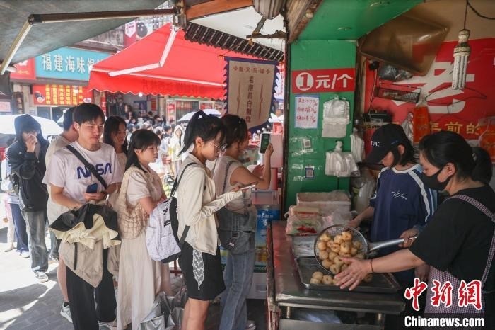 5月2日，江西南昌東湖區，游客在大士院老街的一家商鋪前排隊購買南昌特色美食白糖糕。中新社記者 劉力鑫 攝