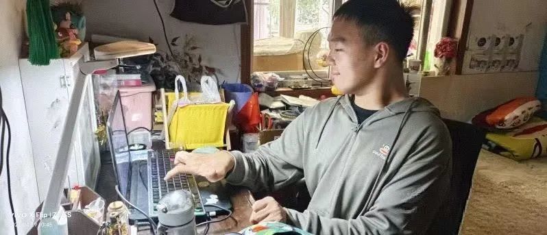 ▲邓添来在书桌的笔记本前整理资料。