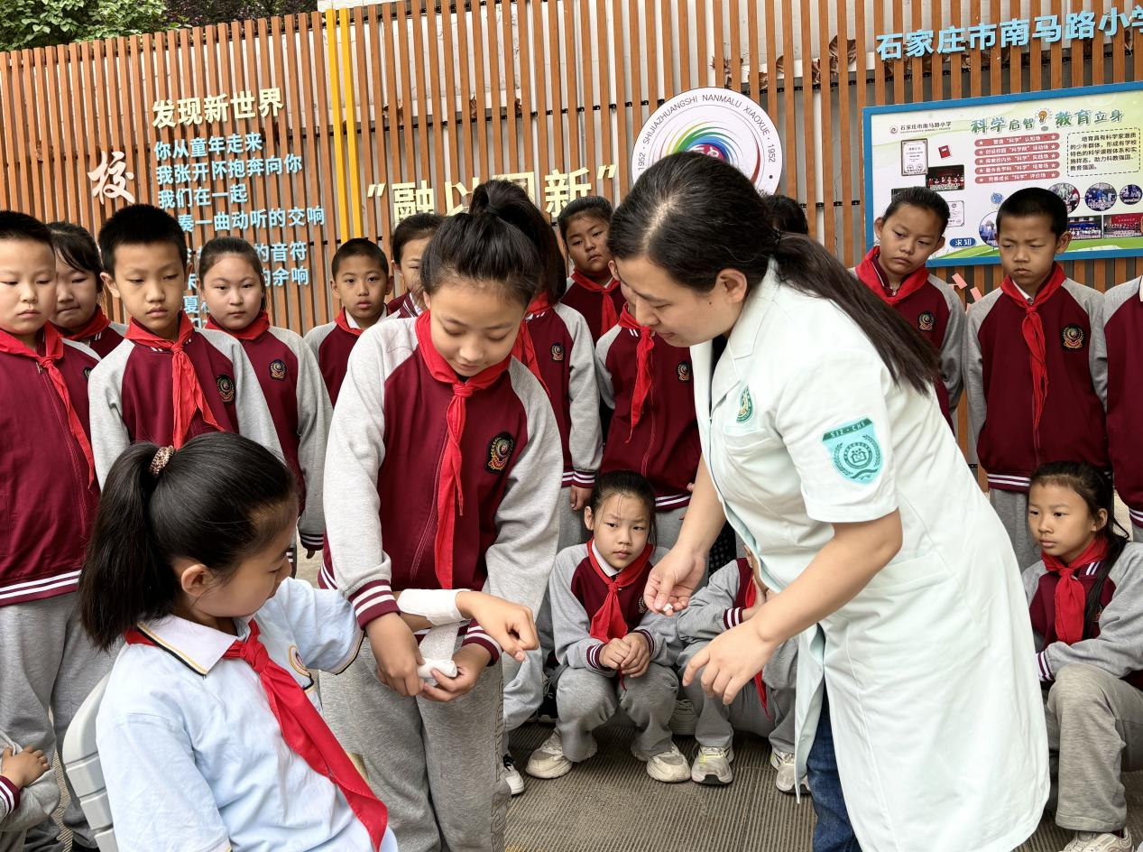 （石家庄市南马路小学的学生在医护人员的指导下练习包扎技能）冯春艳摄