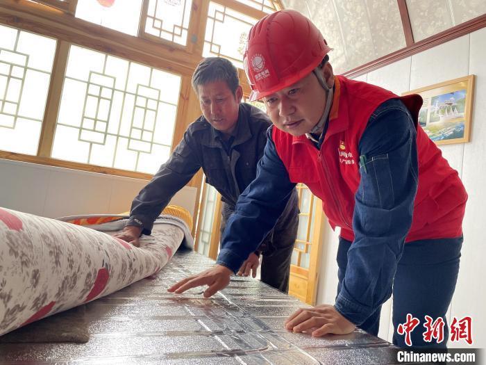 何建功（右）帮助村民消除电热炕用电安全隐患（资料图）　陈高凤　摄