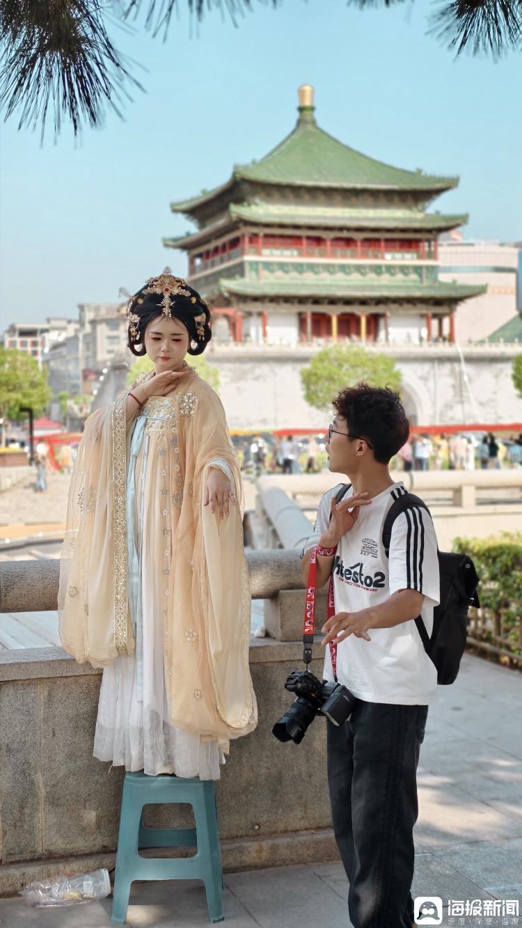 在西安钟楼前一位摄影师在指导顾客摆拍照的姿势