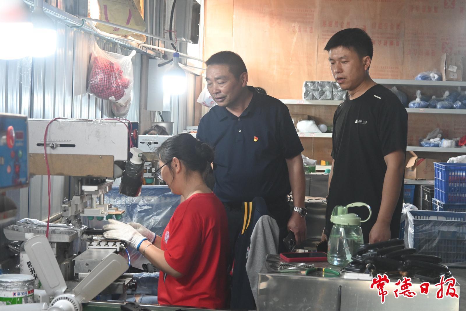 张祖爱(左二)与在玩具厂工作的村民交流