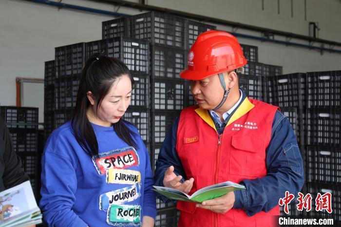 何建功(右)为村民讲解安全用电基本常识　陈高凤　摄