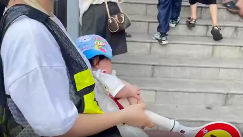 广西百色家长背婴儿执勤护学岗，教育局：自愿参与