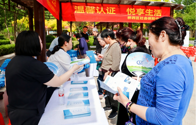 工作人员为群众发放宣传品（石家庄市桥西区社会保险中心供图）
