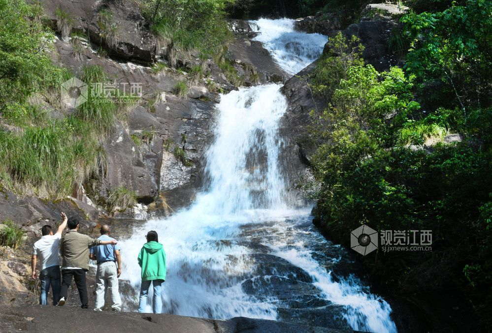 2025年5月10日，游客在江西省德兴市大茅山梧风洞景区银河飞瀑观看瀑布美景。