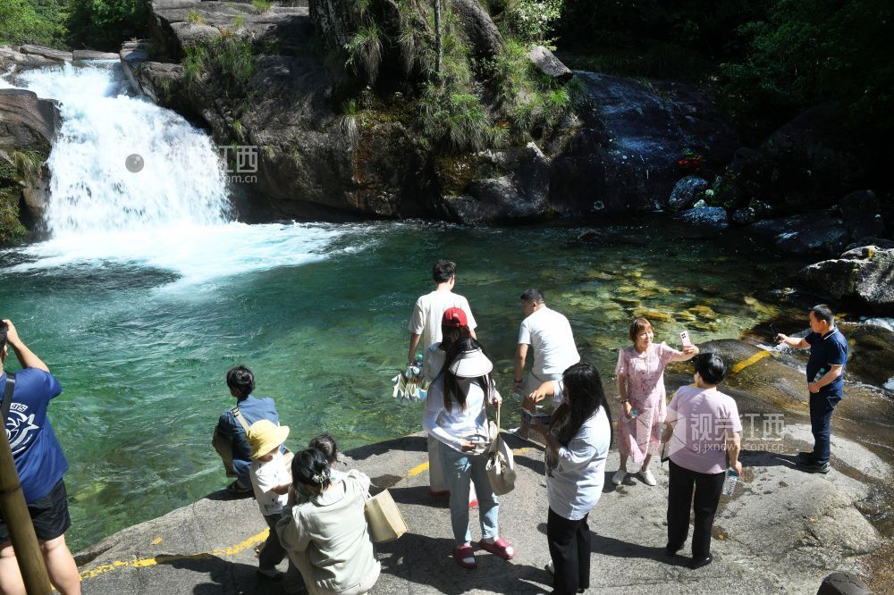 2025年5月10日，游客在江西省德兴市大茅山梧风洞景区仙女潭观看瀑布美景。