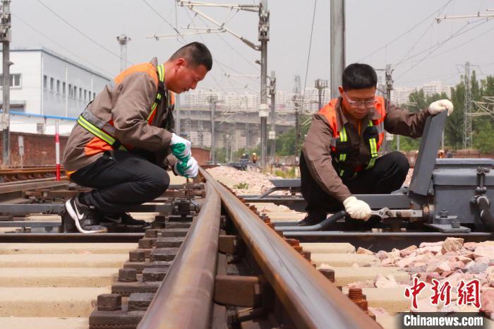 图为张凡和工友正在检修道岔外锁设备。闫怀泽 摄