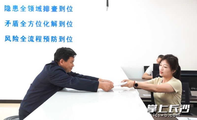 宁乡市夏铎铺镇综治中心里，村民向工作人员递交申请材料。