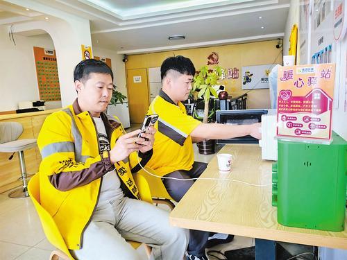 日前，两位外卖骑手在双桥区一处暖心驿站内充电、热饭。本报记者 陈宝云摄
