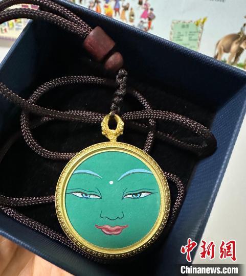 图为藏族画师扎西当知布绘制的佛眼小唐卡饰品,受到游客的喜爱。中新社记者 丁思 摄