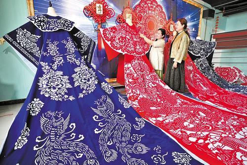 5月8日，衡水滨湖新区剪纸艺人李娜（左）向朋友介绍她新创作的布艺剪纸汉服。