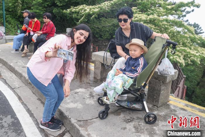 5月16日,江西庐山,来自巴基斯坦的网络达人乔木在含鄱口附近与游人互动拍摄视频素材。中新社记者 刘力鑫 摄