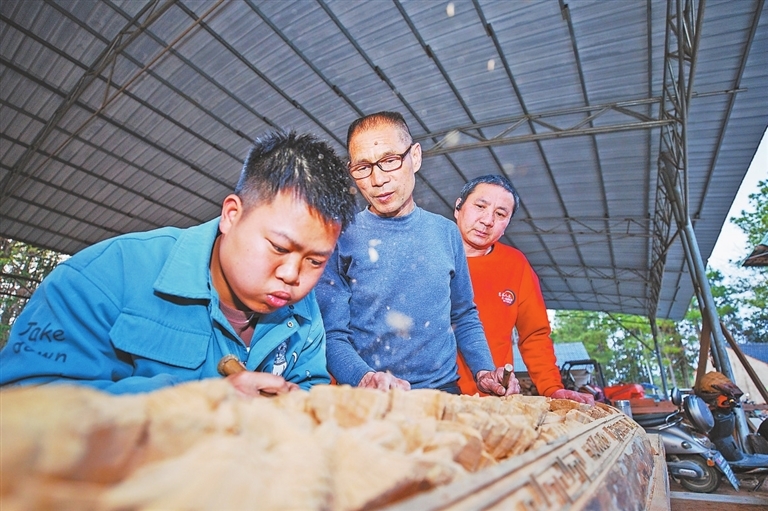 陈乐平（中）指导徒弟提升木雕技艺。