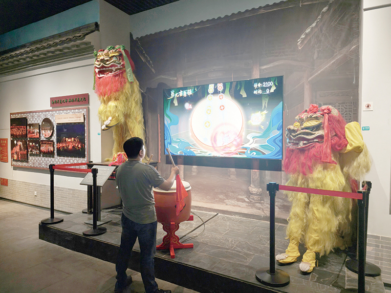 游客在宜春市博物非遗展区尝试击鼓互动体验。