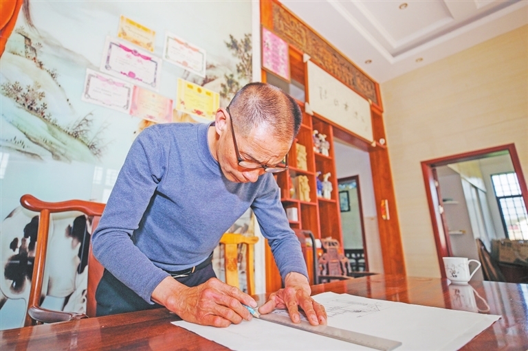 陈乐平在家中绘制古戏台建设图纸。