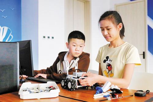 5月21日，在丰南区胥各庄镇银丰中学机器人教室，学生们正在对机器人进行优化。 本报记者师源摄