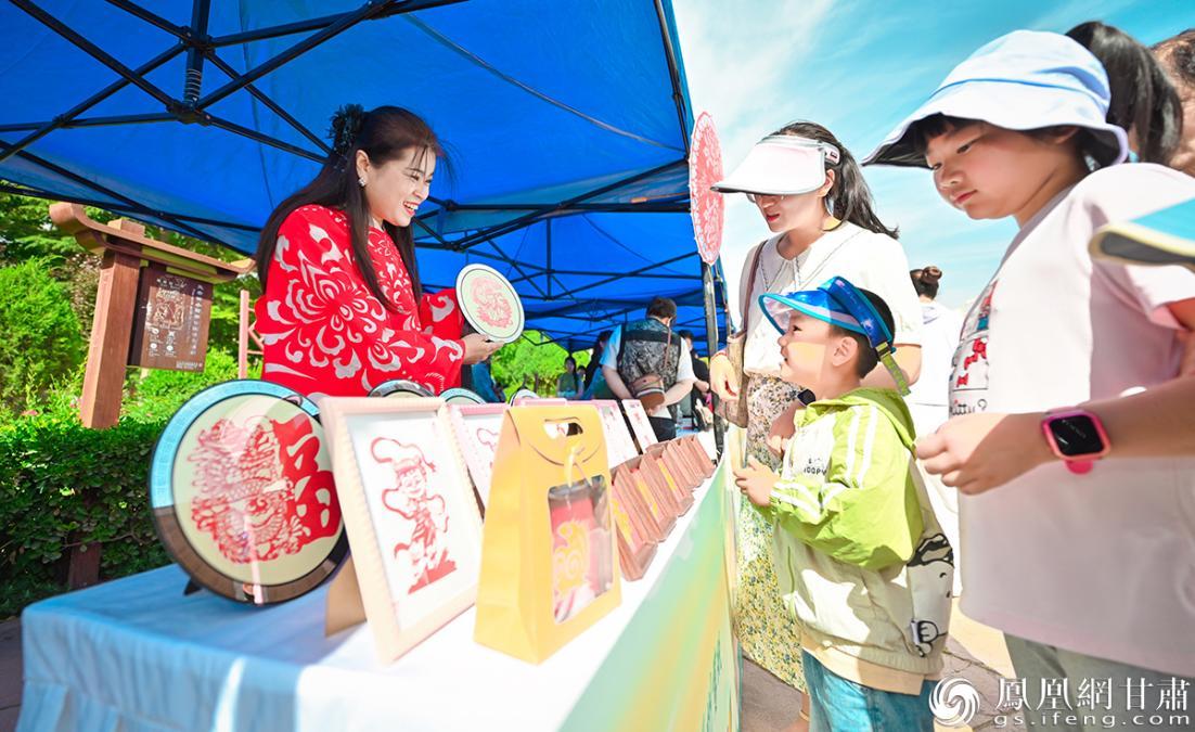 中国高级工艺美术设计师、剪纸非遗传承人杨树珍（左）向市民展示剪纸作品