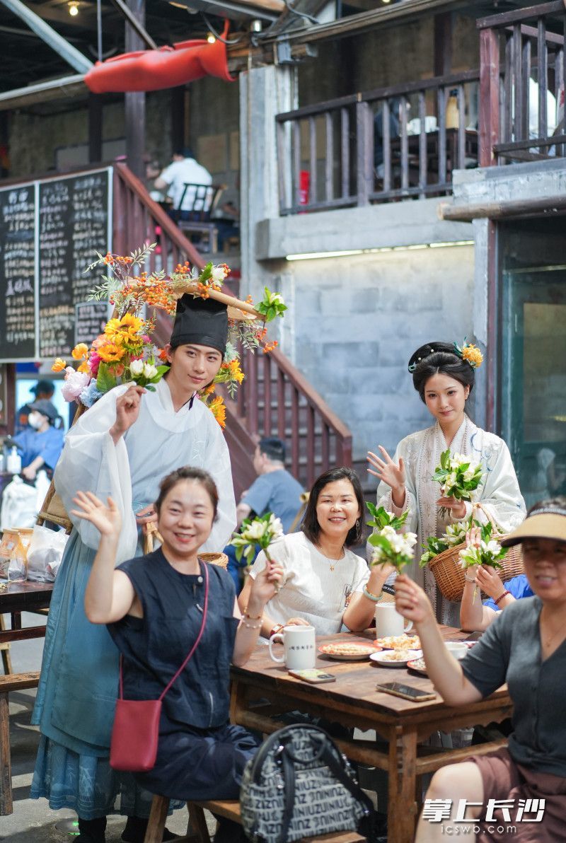 盛装打扮的簪花郎走进东茅街茶馆给市民送栀子花。