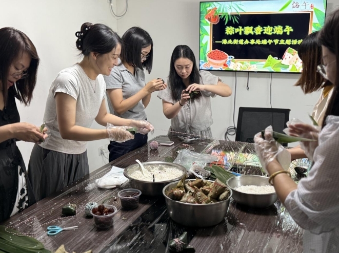 工作人员与居民齐动手包粽子。李静 摄