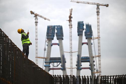 ▲5月28日,渝万高铁石沱长江大桥首个主塔实现封顶,中铁大桥局的技术工人正在指挥高空作业。 记者 罗斌 摄