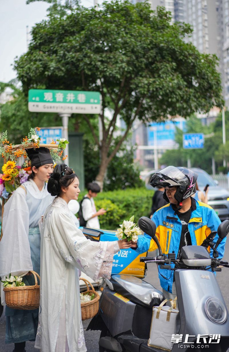 盛装打扮的簪花郎走上长沙街头给外面小哥送栀子花。
