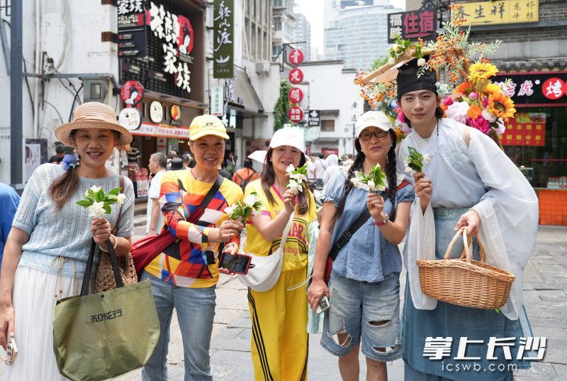 盛装打扮的簪花郎走到太平老街给游客送栀子花。